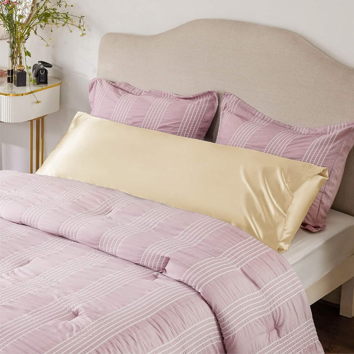 GentleSoft satin body pillowcase in soft gold on a bed with pink striped bedding, enhancing bedroom decor and comfort.