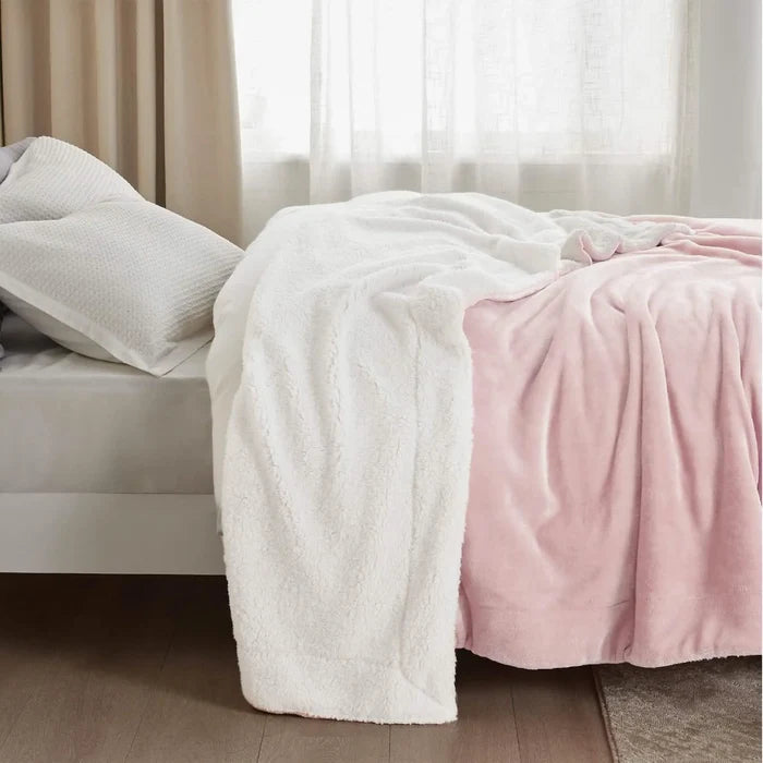 Pink and white dual-sided GentleSoft Sherpa Fleece Blanket on bed, showing soft flannel and plush sherpa textures.