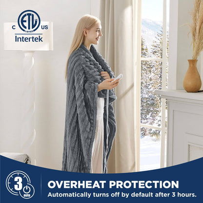 Woman smiles, wrapped in gray GentleSoft striped flannel heated blanket, holding controller, winter scene.
