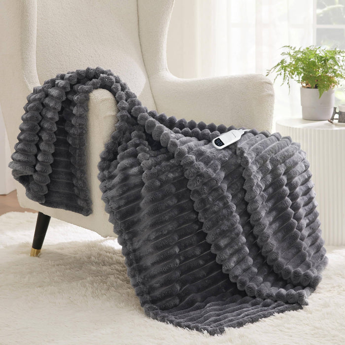 Dark gray textured flannel heated blanket with sherpa reverse draped over armchair, showing controller.