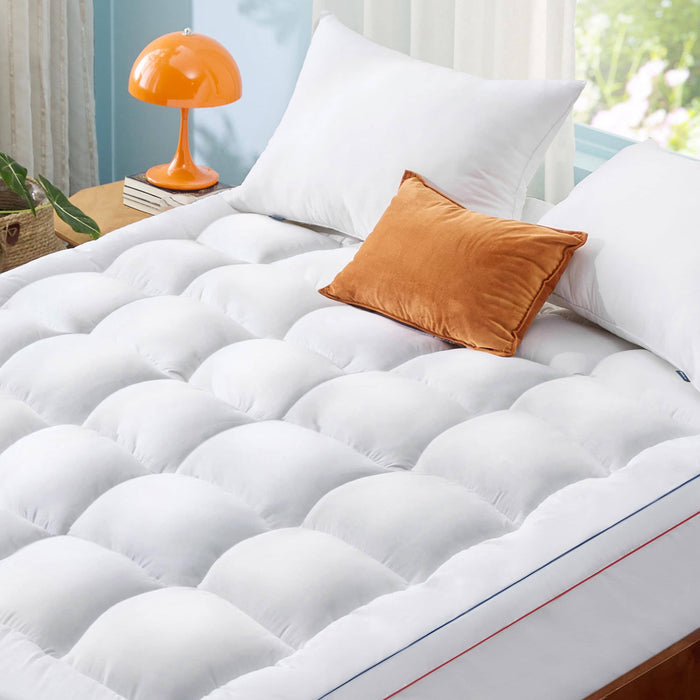 GentleSoft white quilted mattress topper with plush fill and orange accent pillow, showcasing comfort on a bed.