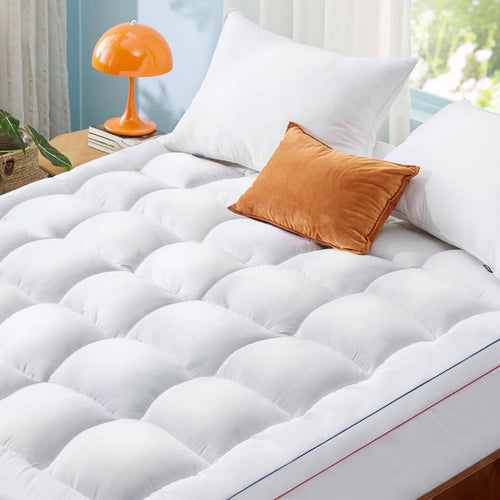 GentleSoft white quilted mattress topper with plush fill and orange accent pillow, showcasing comfort on a bed.