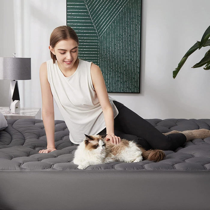 Three-zone gray quilted mattress pad with woman and cat relaxing.