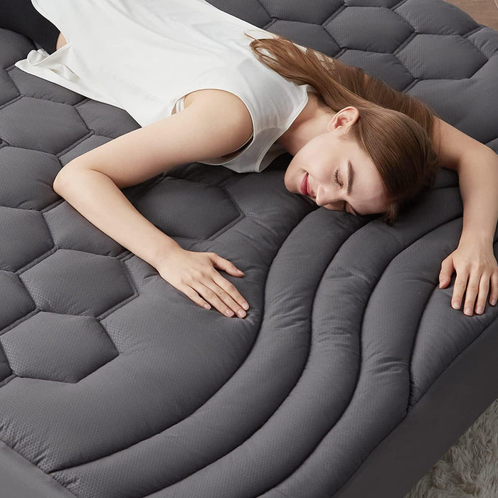 Grey Three-Zone quilted mattress pad with honeycomb and wave pattern, woman resting.