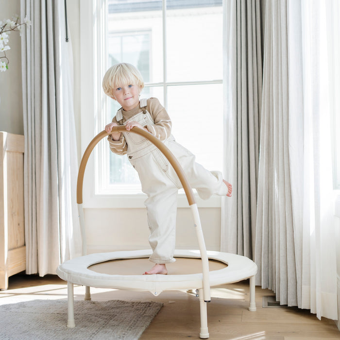 Ivory / Classic@Child using a low-profile indoor trampoline designed for balance and movement