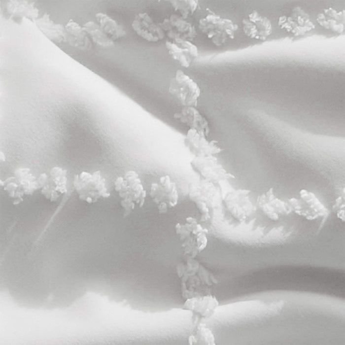 Close-up of white GentleSoft comforter showing diamond tufted embroidery and soft polyester texture on product page.
