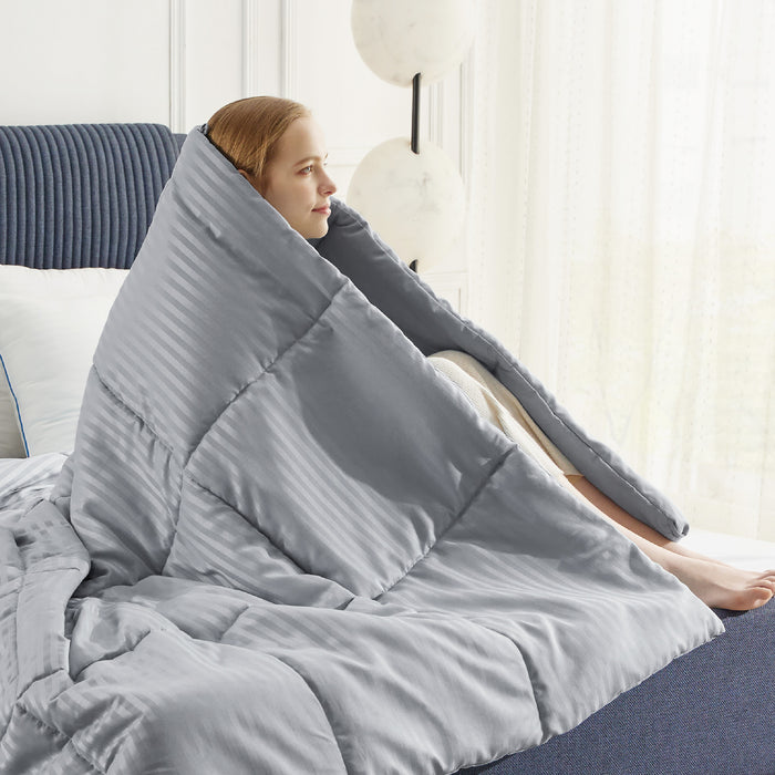 Grey striped weightless comfy quilt draped around woman on bed.
