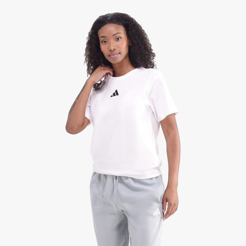 Young Black woman modeling a white Adidas short sleeve t-shirt with a black logo, paired with light blue Adidas sweatpants.